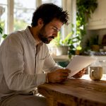 Chez lui, un homme prend le temps de s’informer sur les compléments alimentaires dédiés à la fertilité en lisant un article spécialisé.