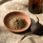 Racine de maca noire et poudre présentées sur une assiette rustique
