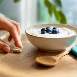 Main tenant une capsule de maca avec un repas