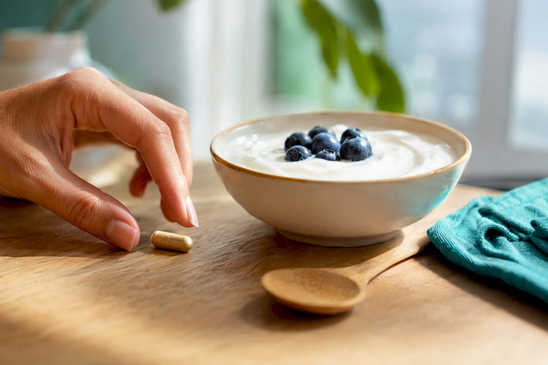 Main tenant une capsule de maca avec un repas