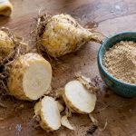 Racines fraîches de maca et poudre posées sur un plan de travail