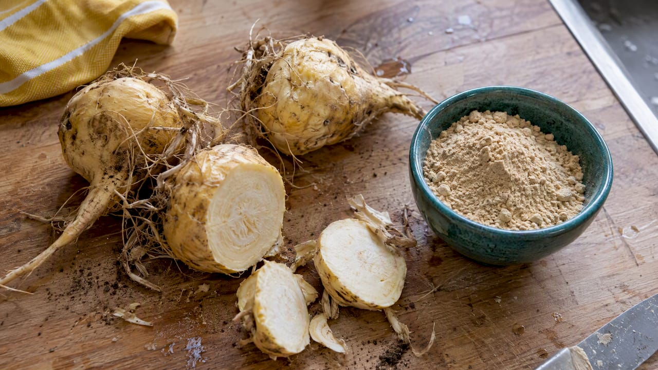 Racines fraîches de maca et poudre posées sur un plan de travail
